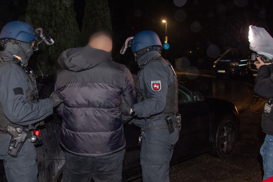 Ein Verdächtiger (2.v.l.) wird von Einsatzkräften der Polizei abgeführt.