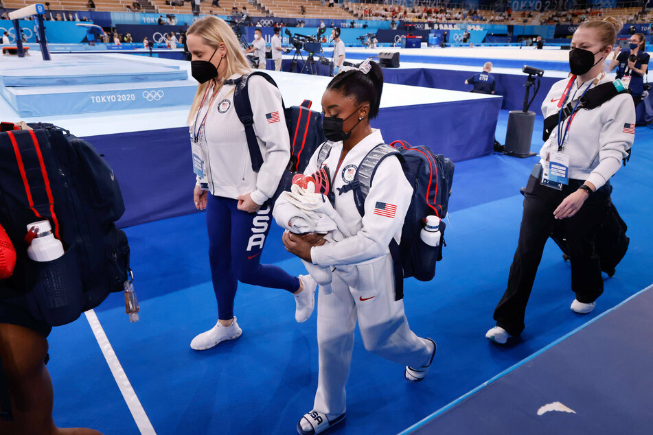 Simone Biles (c.) walked with her team to the balance beam after dropping out of the team finals on Tuesday at the Tokyo Olympics.