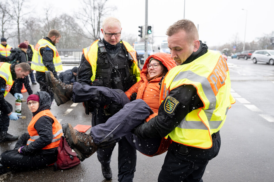 Eine Klimaaktivistin wird von der Polizei kurzerhand weggetragen.