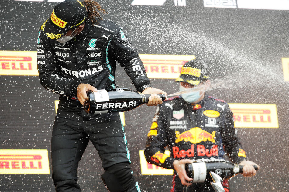 Max Verstappen (r.) feiert seinen ersten Saisonsieg neben dem Zweitplatzierten Lewis Hamilton.