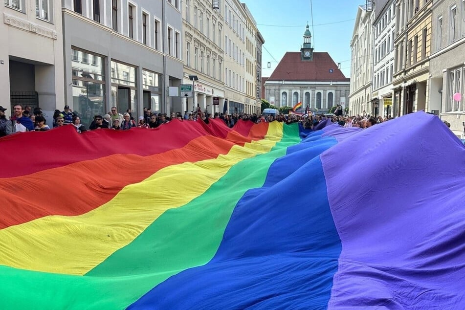 Teilnehmer ziehen mit einer überdiemensionalen Regenbogenfahne beim 4. Christopher Street Day (CSD) durch die Stadt.
