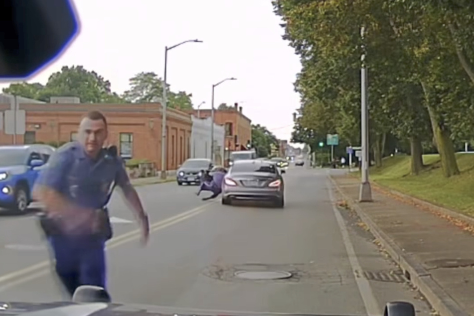 Ein Officer rannte zurück zum Polizeiauto, während sein Kollege aus dem silbernen Mercedes geworfen wurde.