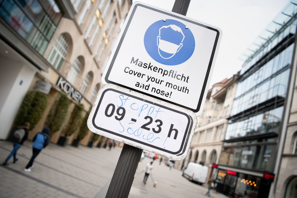 Ein Schild mit der Aufschrift "Maskenpflicht - Cover your mouth and nose! - 09 - 23h" weist in der Innenstadt von München auf die Maskenpflicht zwischen 9 Uhr morgens und 23 Uhr abends hin.