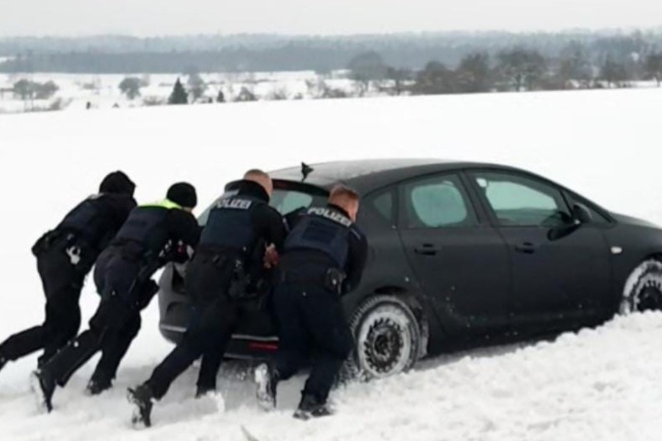 Polizisten schieben Opel Astra aus dem Straßengraben