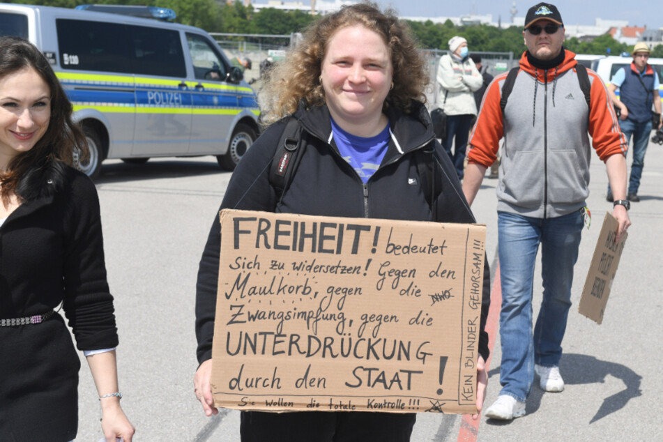 Eine Demonstrantin trägt ein Schild mit der Aufschrift "Freiheit bedeutet sich zu widersetzen! gegen ......" und kommt damit auf die Theresienwiese.