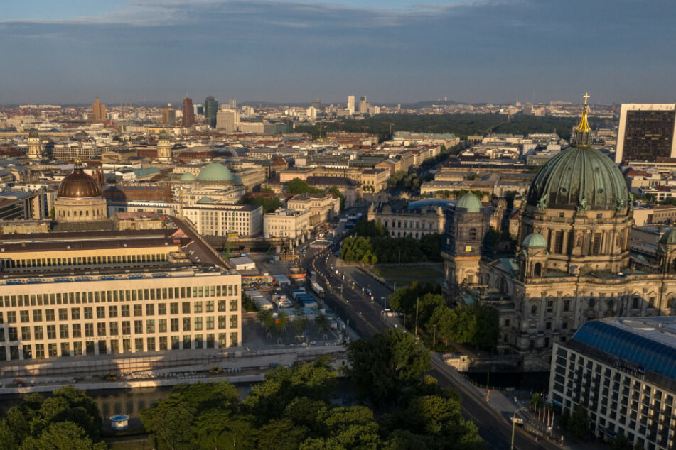 Das Humboldt-Forum wird von den warmen Strahlen der aufgehenden Sonne angeleuchtet. Rechts ist der Berliner Dom zu sehen.