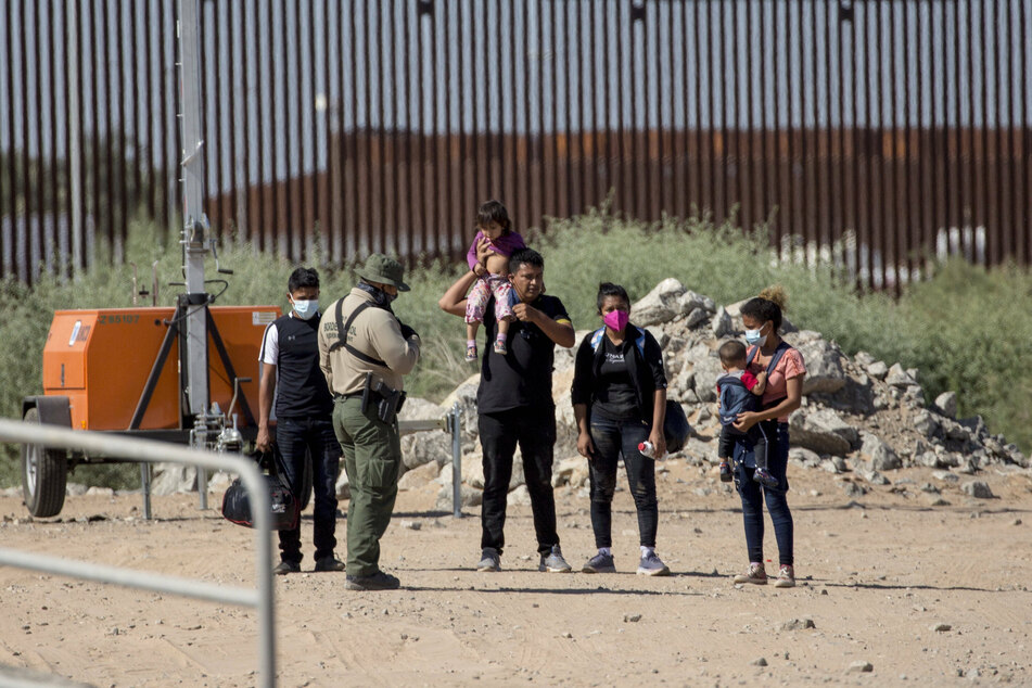 Migrants from Guatemala turn themselves over to a Border Patrol agent after crossing the border wall between the United States and Mexico.