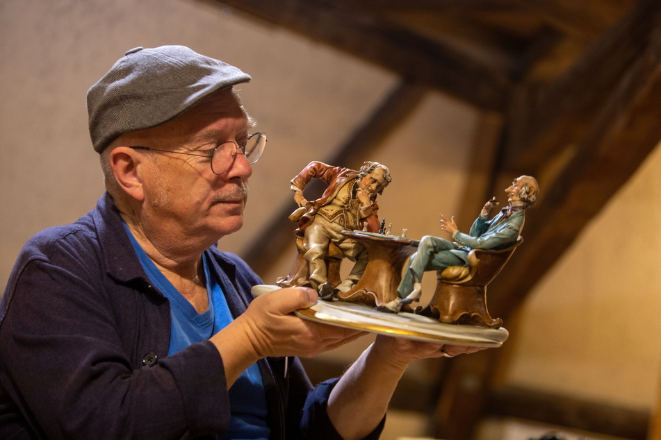 Klaus Noack (69) von der Malzhausgalerie betrachtet diese beiden schachspielenden Herren aus Porzellan.