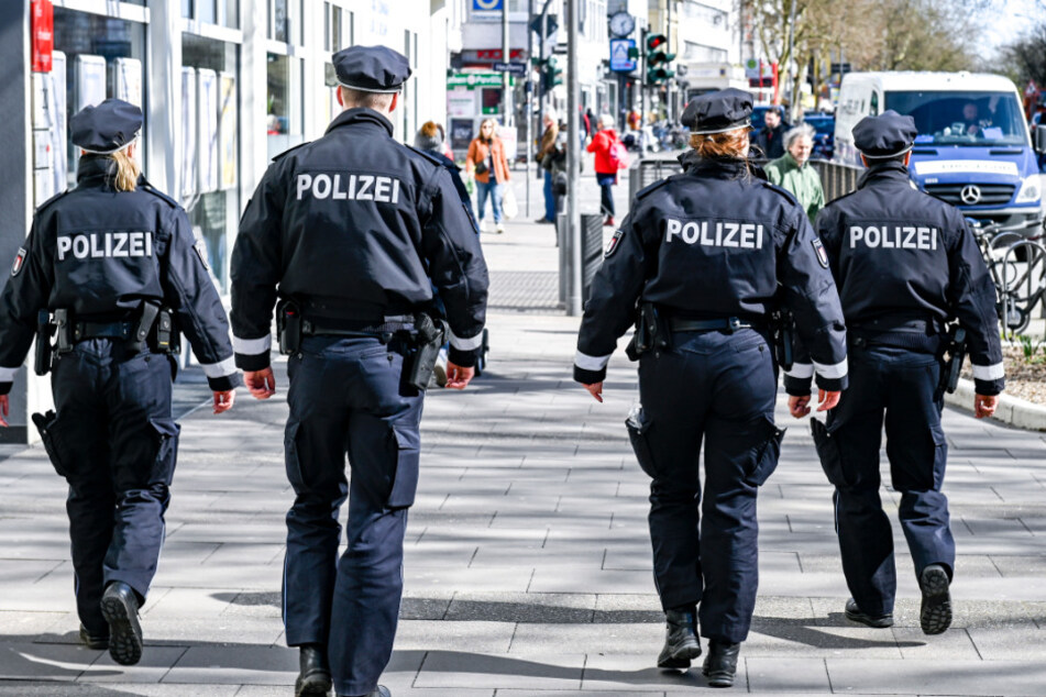 Polizisten patrouillieren vor dem Eingang zu einem Supermarkt auf einer Einkaufsstraße in Hamburg. 