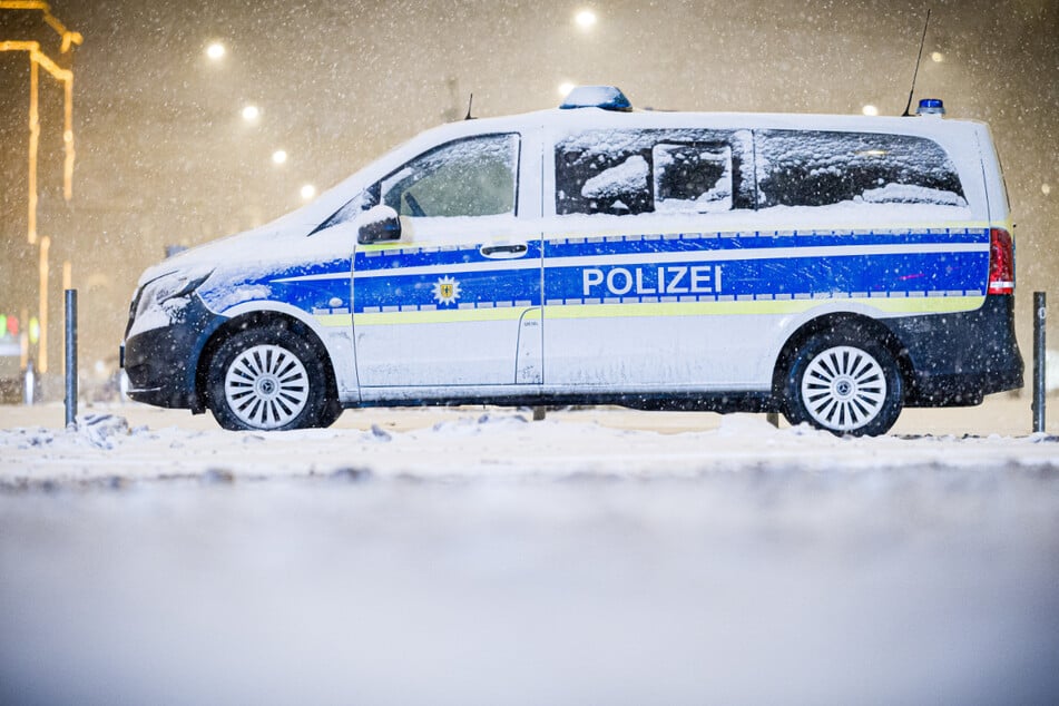 Ein Einsatzfahrzeug der Polizei am frühen Morgen im dichten Schneefall.