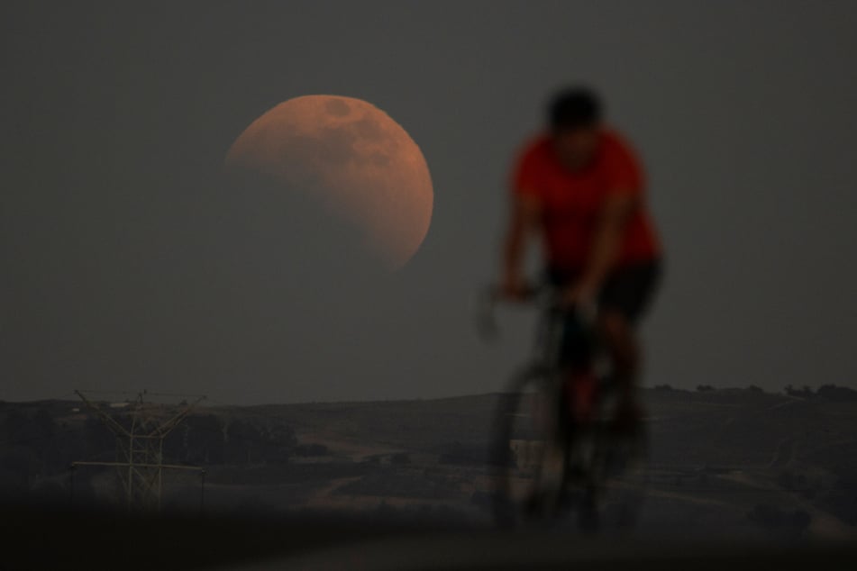 Eine Mondfinsternis ist hinter einem Radfahrer in Irwindale (USA) während des ersten Blutmonds des Jahres zu sehen.