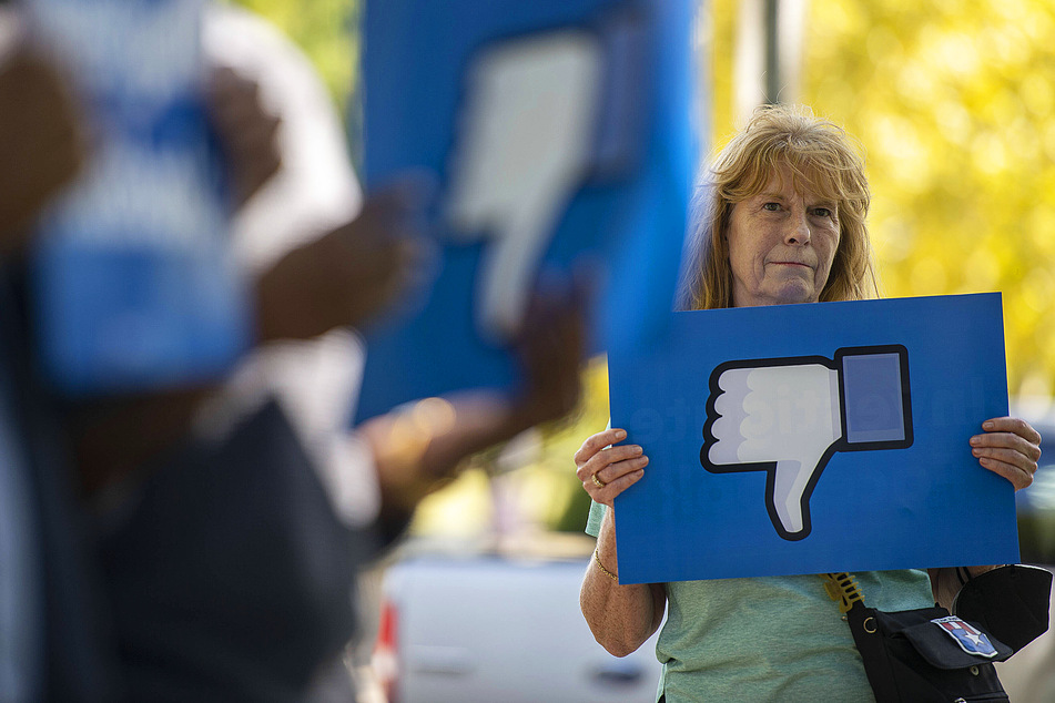 A woman holds a reversed like button at the September 30 Free Action Press rally demanding Facebook ban Team Trump advertisements in accordance with their June decision.