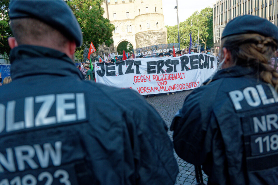 Teilnehmer einer Spontandemonstration in Köln halten ein Plakat mit der Aufschrift: "Jetzt erst recht, gegen Polizeigewalt und Versammlungsgesetz".
