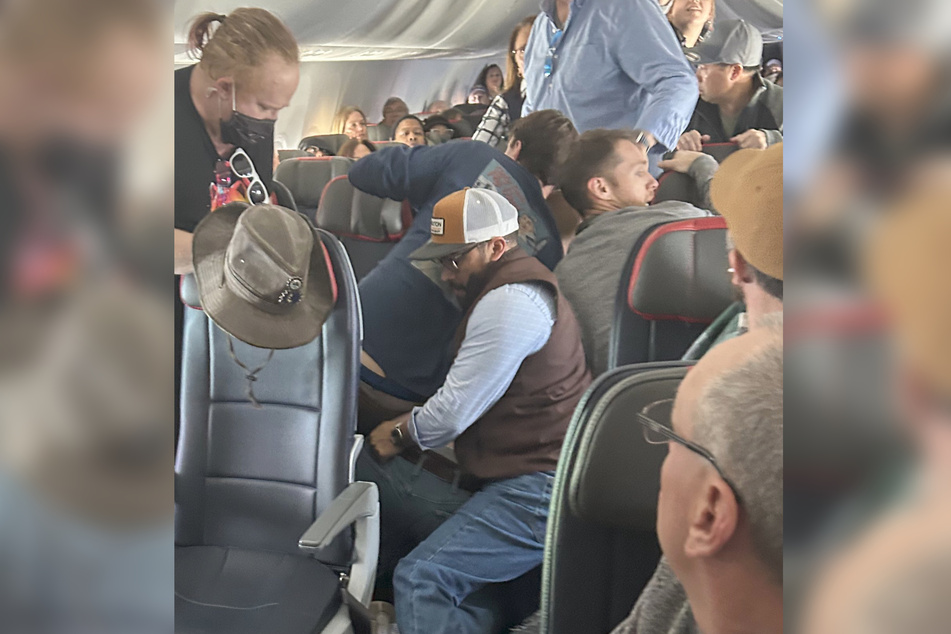 In einem Flugzeuggang ist nicht viel Platz. Aber genug, um zu fünft einen verrückten Passagier in Schach zu halten.