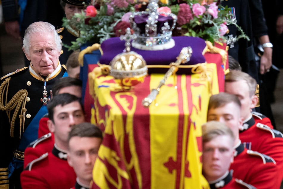 King Charles III (l.) walks behind the coffin of his mother, Queen Elizabeth II.