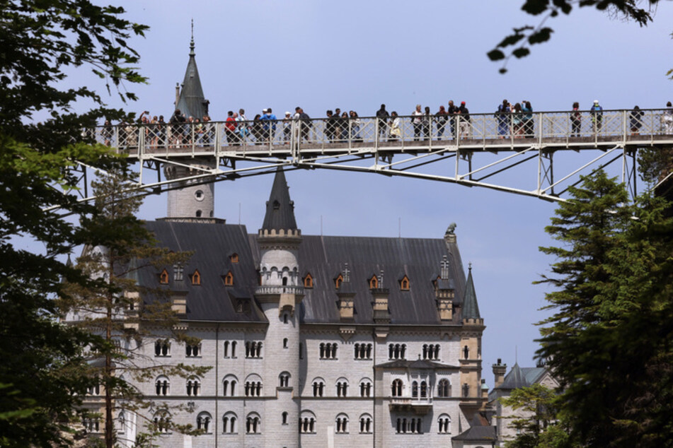 Touristen stehen auf der Marienbrücke vor dem Schloss Neuschwanstein. Ein Mann stieß im Sommer 2023 unweit von hier zwei Touristinnen in die Schlucht. (Archivbild)