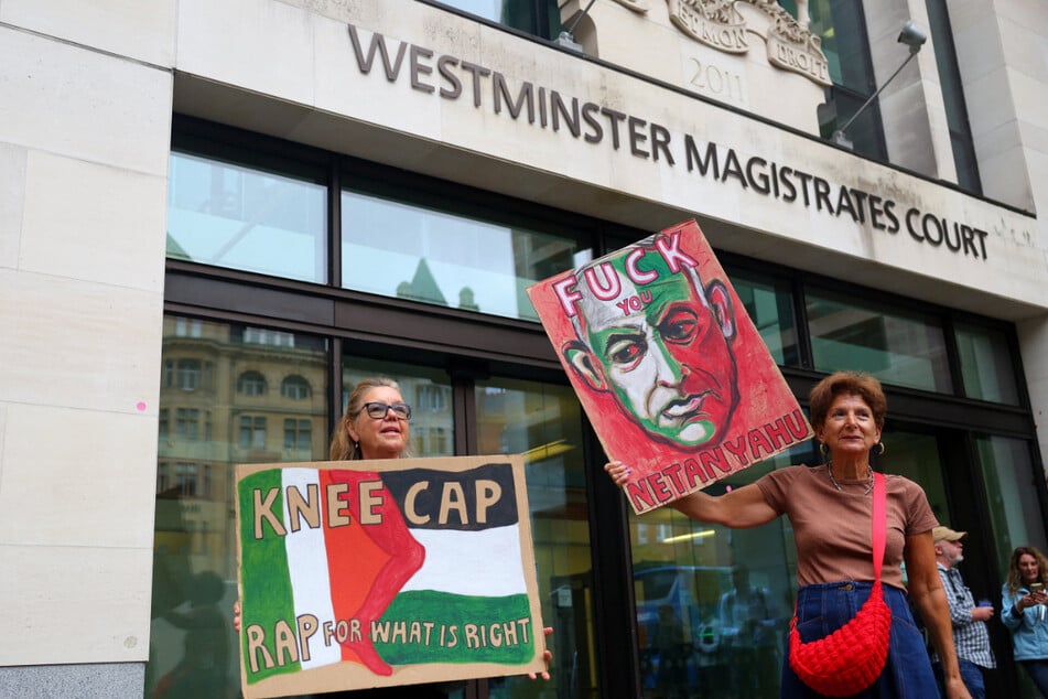 Supporters of Kneecap member Liam O'Hanna raise protest signs outside the Westminster Magistrates' Court in London on August 20, 2025.