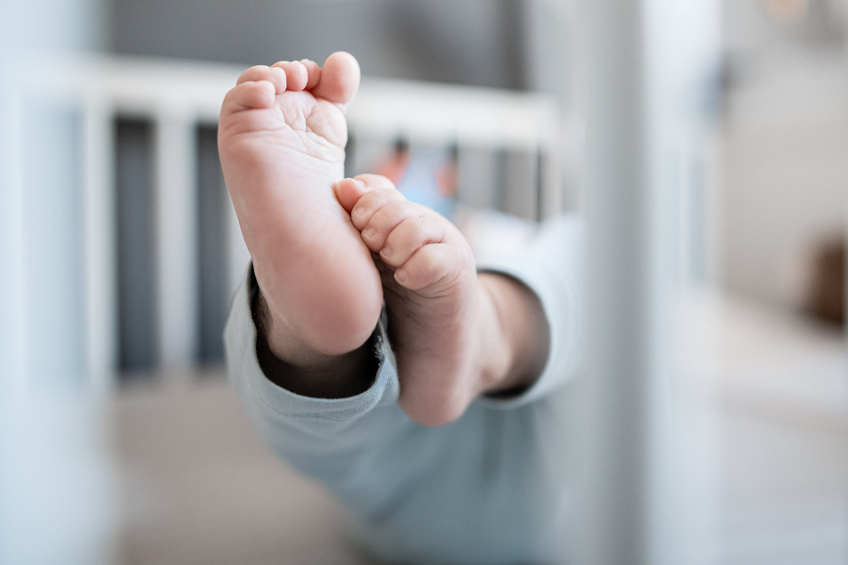 Die Füße eines Babys sind in einem Kinderbett zu sehen. (Symbolbild)
