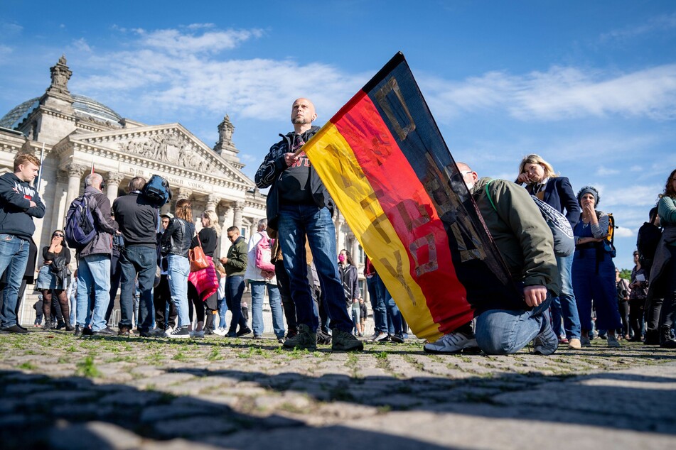 Teilnehmer demonstrieren mit einer Deutschlandfahne vor dem Reichstagsgebäude gegen eine Impfpflicht und gegen die Freiheitseinschränkenden Maßnahmen der Bundesregierung im Rahmen der Ausbreitung des Coronavirus.