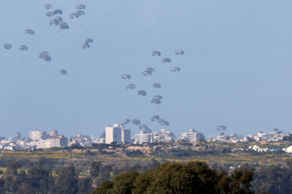 Humanitarian aid falls over northern Gaza as seen from Israel's southern border with the Gaza Strip on Thursday.