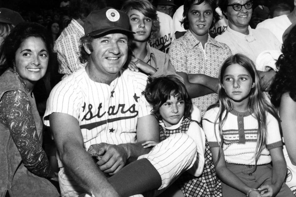 Gene Hackman (second from l.) in uniform for the Stars at a Dodgers Hollywood Stars game, where celebrities get to play a baseball game with major league athletes. Hackman sits among fans with his then-wife, Faye Matese, (l.), and two daughters Elizabeth and Leslie (r.)