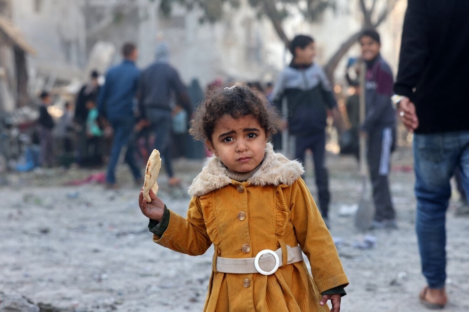 A Palestinian girl eats a piece of bread following overnight Israeli air strikes on the Rafah refugee camp in the southern Gaza Strip.