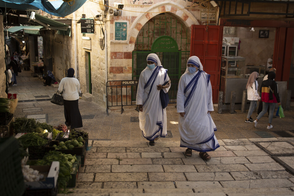 Katholische Nonnen gehen mit Mund-Nasen-Schutz über einen Platz in der Altstadt von Jerusalem.