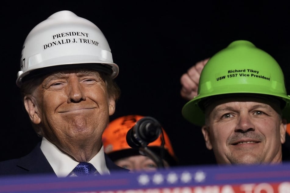 Donald Trump wears a hard hat and stands with United Steel Workers Local 1557 Vice President Richard Tikey during a campaign rally on October 19, 2024, in Latrobe, Pennsylvania.