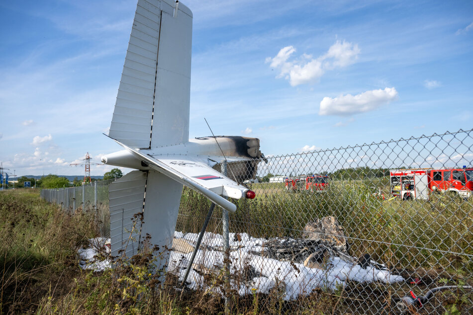 Trümmerteile des Kleinflugzeugs hängen in einem Zaun.