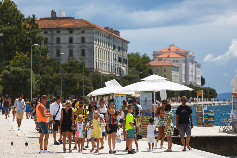 Touristen spazieren an der Uferpromenade im kroatischen Zadar entlang.