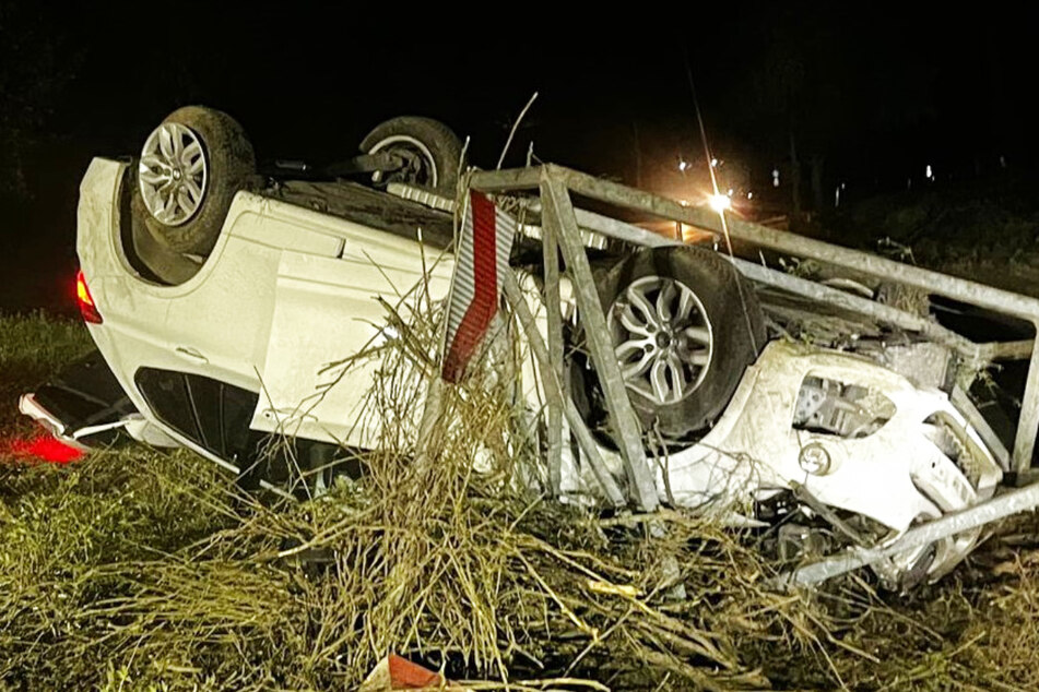 Unfall auf der K23 bei Speyer: Ein weißer BMW überschlug sich und landete nach etwa zehn Metern und auf dem Dach liegend als verbeultes Wrack.