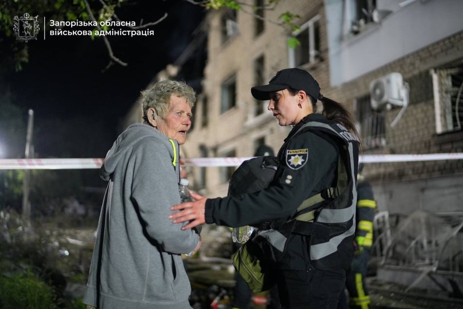 Einsatzkräfte kümmern sich um eine Frau, die mitten in der Nacht von den Russen ausgebombt wurde.