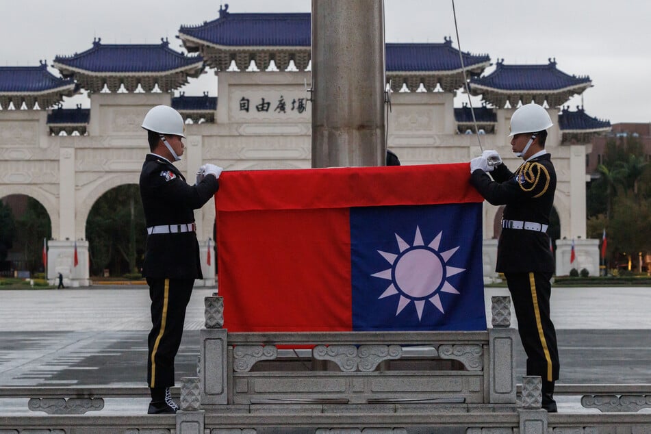 CHENG YU-CHEN / AFP Photo by CHENG YU-CHEN / AFP TOPSHOT - Taiwan's national flag is raised during an early morning flag-raising ceremony following China's People’s Liberation Army said it would conduct live-fire drills in five designated maritime and airspace areas around Taiwan, in Taipei on December 30, 2025