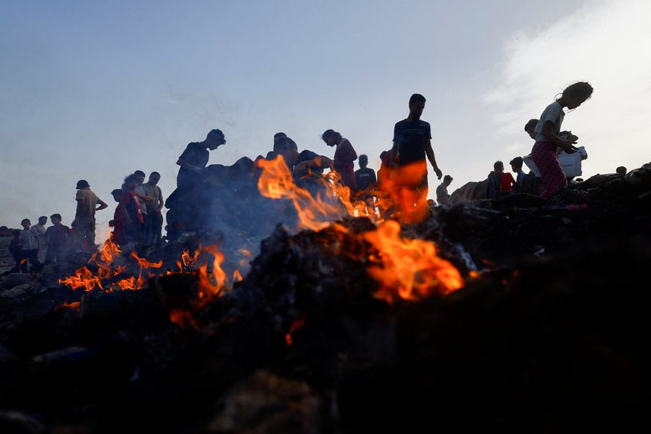 Palestinians search for food among burned debris in the aftermath of an Israeli strike on a Rafah refugee camp.