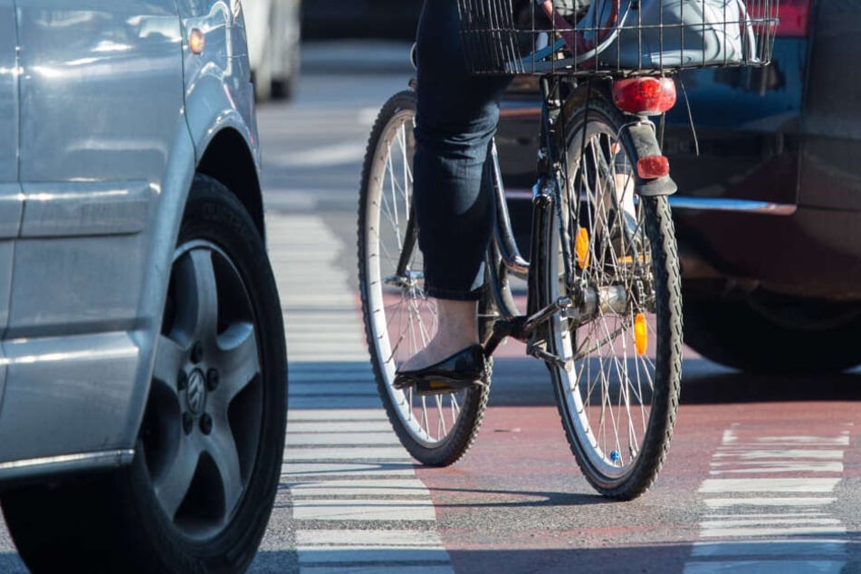 Typische Gefahrensituation: Eine Fahrradfahrerin radelt auf einem Radweg, während Autos rechts abbiegen. (Symbolbild)