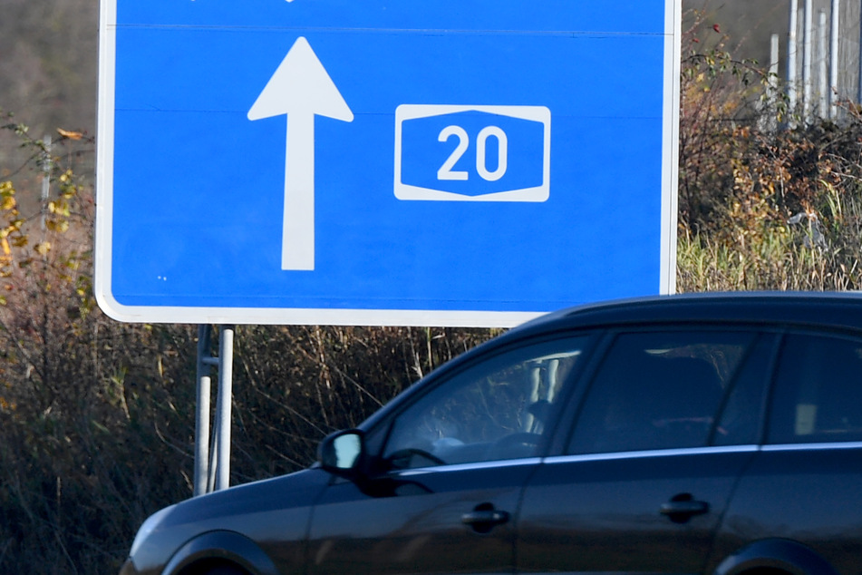 Ein Auto fährt an einem Hinweisschild vorbei auf die Autobahn 20.