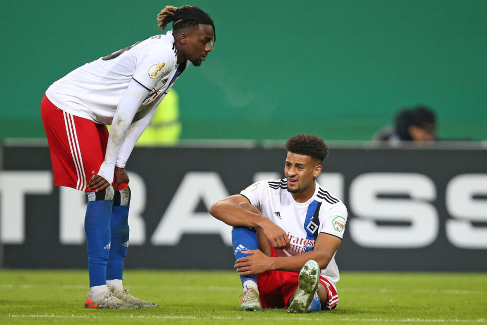 Josha Vagnoman (rechts) sitzt verletzt am Boden. Mitspieler Gideon Jung