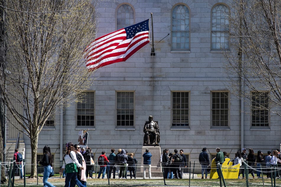 Demonstrators with signs stand around the John Harvard Statue in Harvard Yard following a rally against President Donald Trump’s attacks on Harvard University at Harvard University in Cambridge, Massachusetts on April 17, 2025.