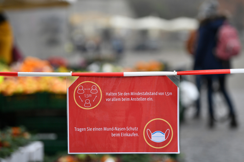 In Erfurt sind Verhaltensregeln für den Wochenmarkt auf einem Schild am Domplatz zu sehen.