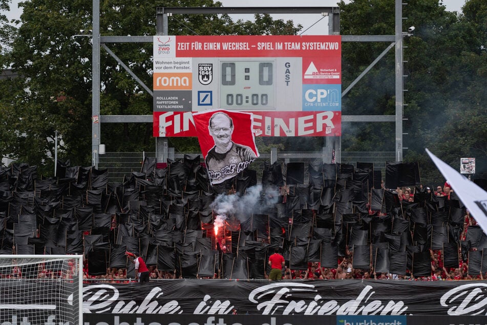 Bewegende Szene vor dem Anpiff, als die Fans eine Fahne für den verstorbenen Zeugwart Peter Miethe (†62) hochhielten.