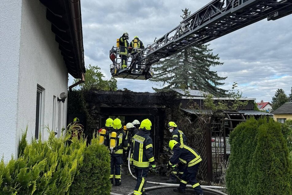 Einsatzkräfte vor Ort: Eine Garage neben einem Einfamilienhaus ist abgefackelt.