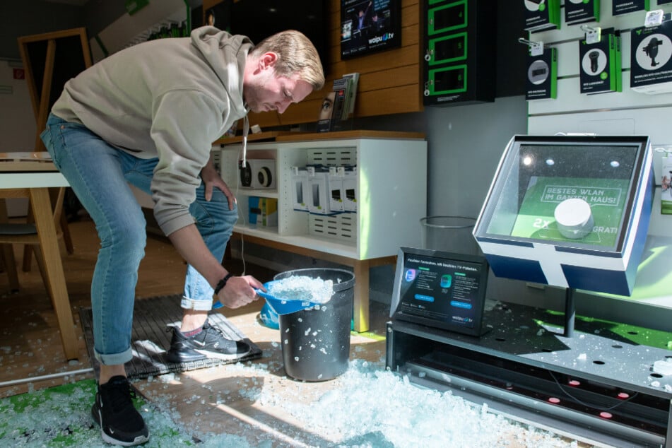 Ein Mitarbeiter eines Handyladens räumt Scherben auf.