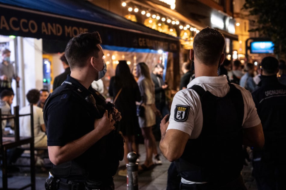 Ein Polizeibeamter und ein Mitarbeiter des Ordnungsamtes stehen vor einem Lokal.