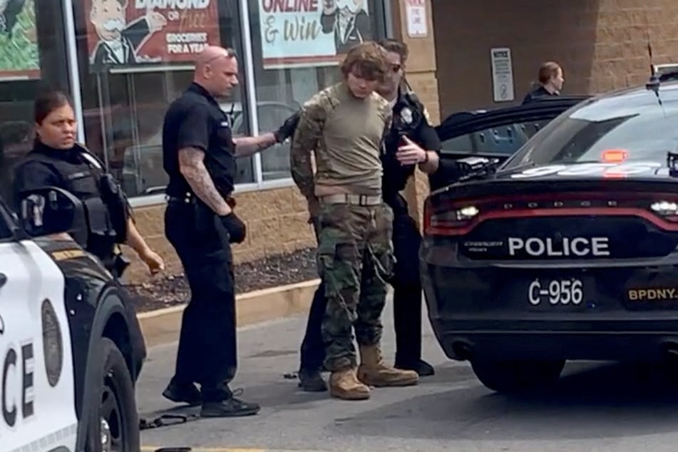 A suspect was detained following a mass shooting in the parking lot of Tops supermarket in Buffalo, New York, in a still image from a social media video.
