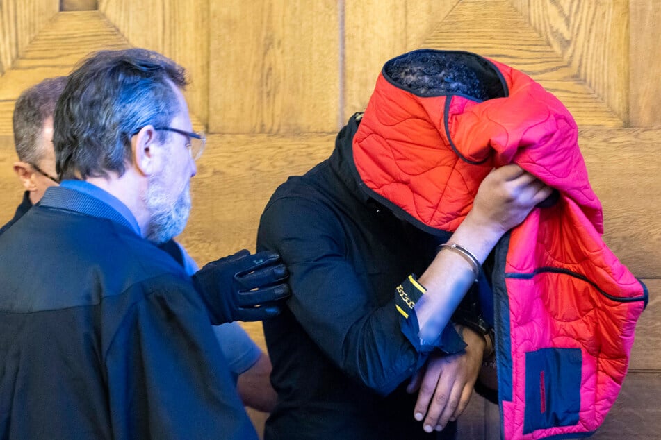 Ammar S. (28) versucht sein Gesicht hinter einer roten Jacke zu verstecken.