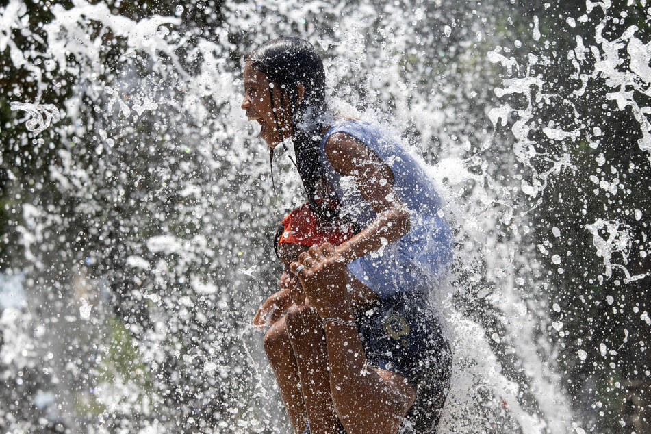 People cool off in a fountain as Houston, Texas, and other southern US cities continue to record dangerously high temperatures.