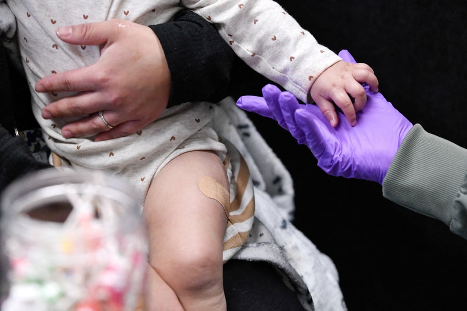 A healthcare worker holds a 13-month-old’s hand after administering the first MMR vaccine dose at the City of Lubbock Health Department in Texas.