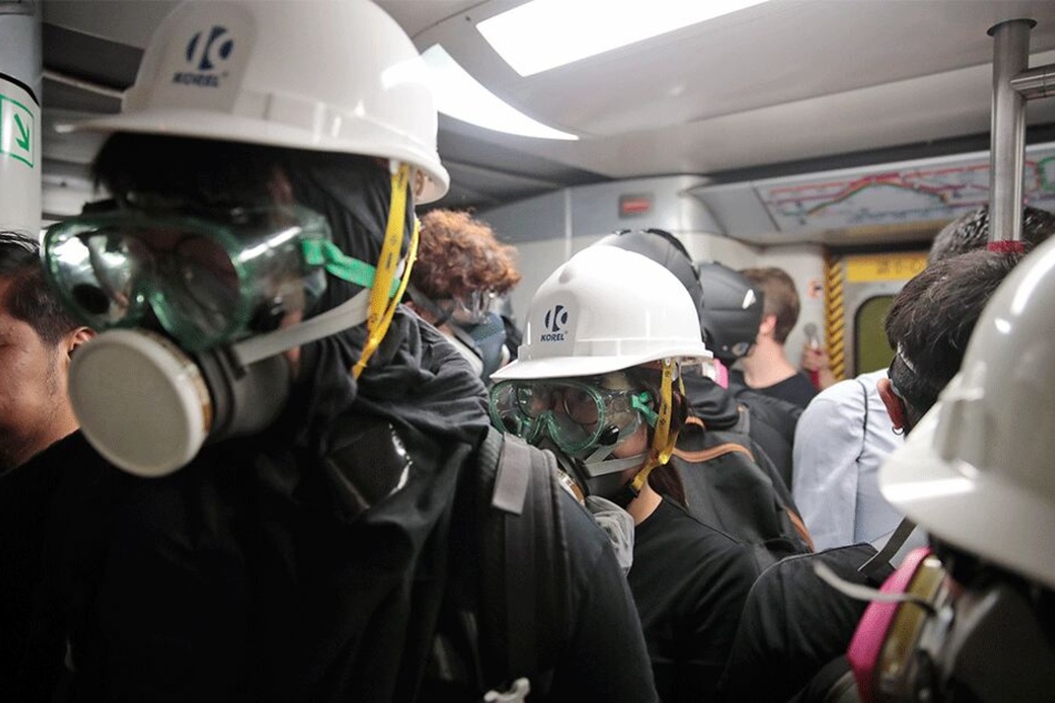 Mit Gasmasken und Helmen ausgestattete Demonstranten fahren im Zug nach Causeway Bay.