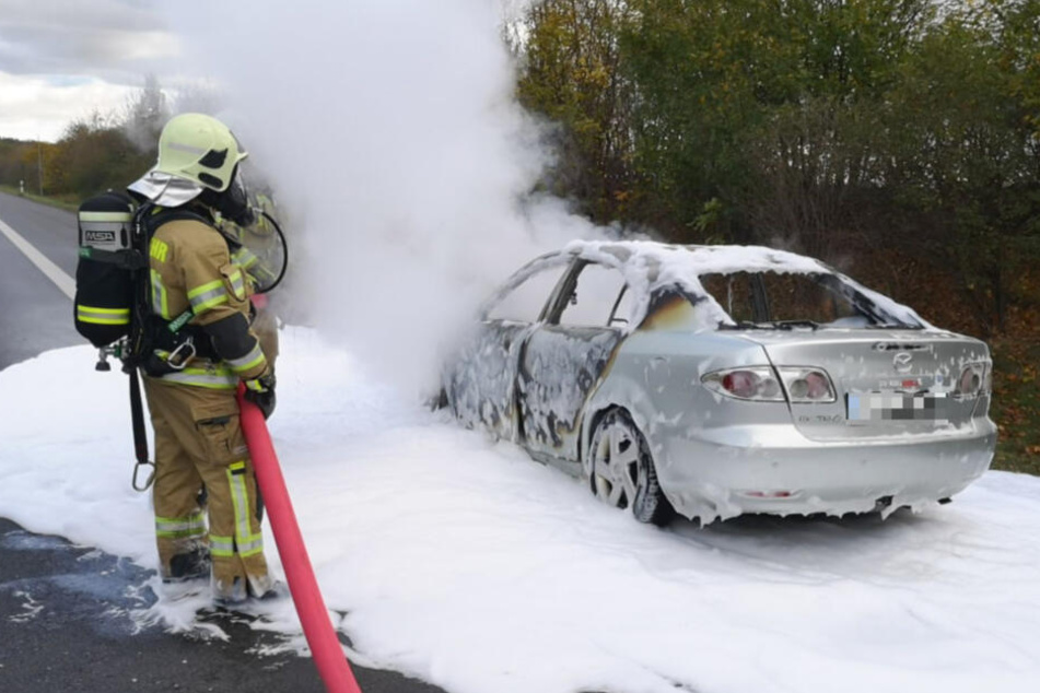 Die Feuerwehr löscht den völlig ausgebrannten Mazda.