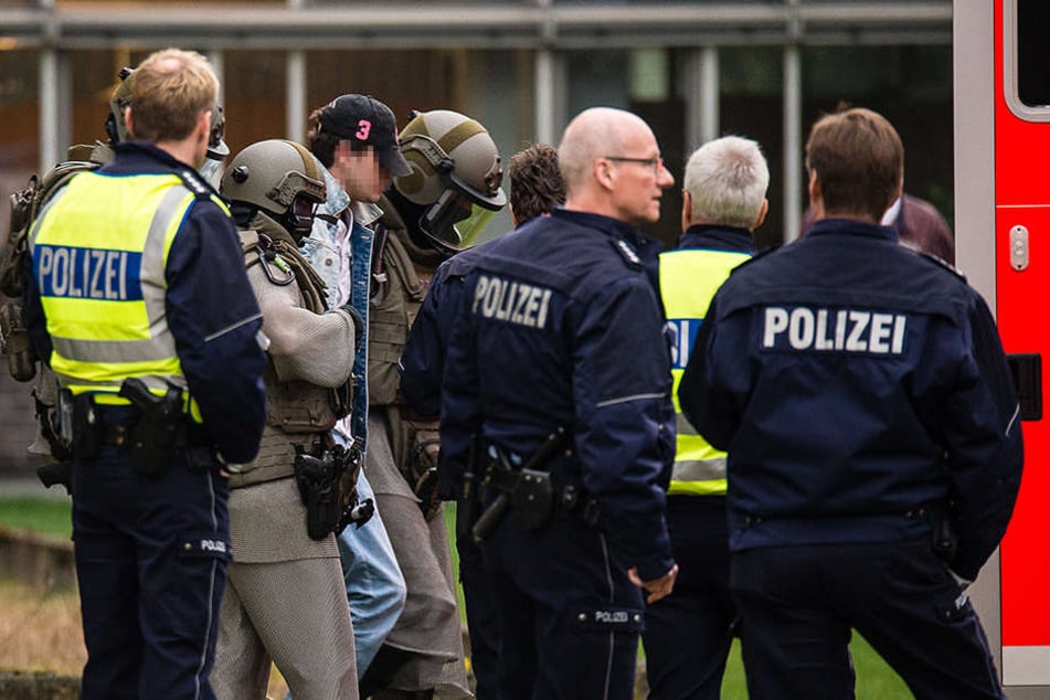Der Mann versteckte sein Gesicht unter einer Baseball-Kappe, als er von der Polizei abgeführt wurde.
